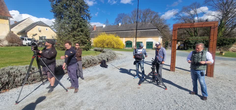 Kamerateam mit Stativ und Tonangel im Schlosshof, im Hintergrund die Wirtschaftsgebäude und blühende Forsythien