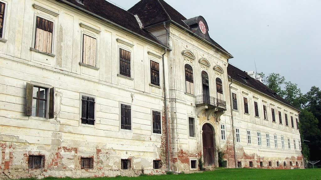 Die lange Schlossfassade vor der Sanierung: abgeblätterter Putz, freiliegende Ziegel, vernagelte Fensterläden